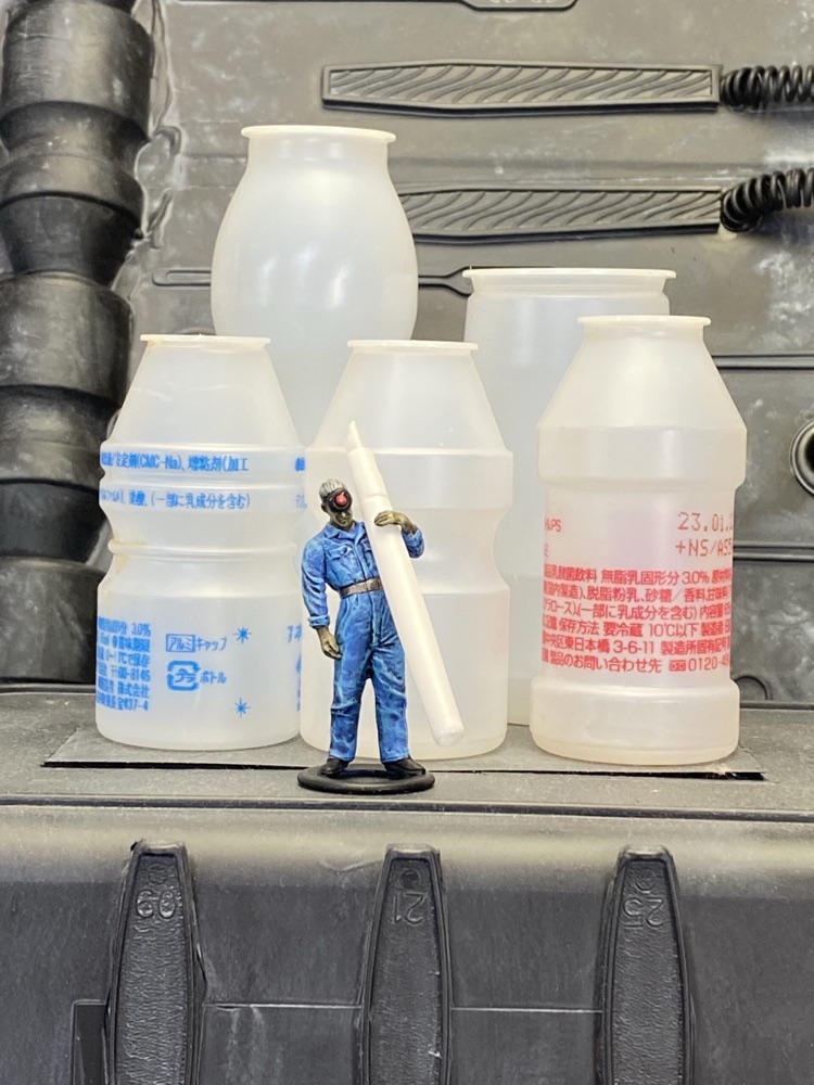 巨大な日用品のボトルがそびえる中に立つ、1/35スケールの整備兵